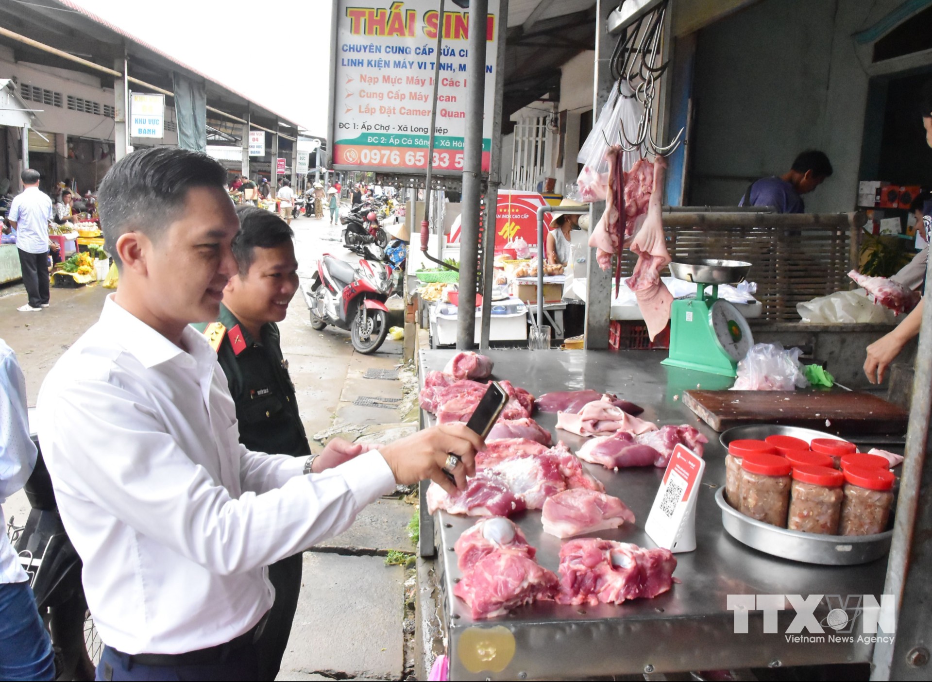 Lãnh đạo xã Long Hiệp tuyên truyền, hướng dẫn tiểu thương thực hiện thanh toán không dùng tiền mặt tại Chợ Long Hiệp. (Ảnh: Thanh Hòa/TTXVN)